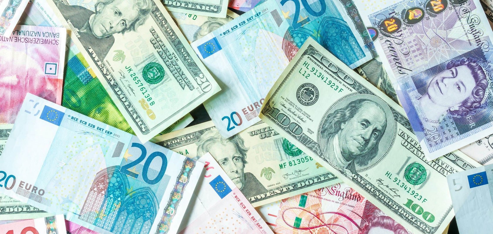 Mehrere Geldscheine verschiedener Währungen, darunter Euro, US-Dollar und Pfund, liegen überlappend auf einer Fläche
