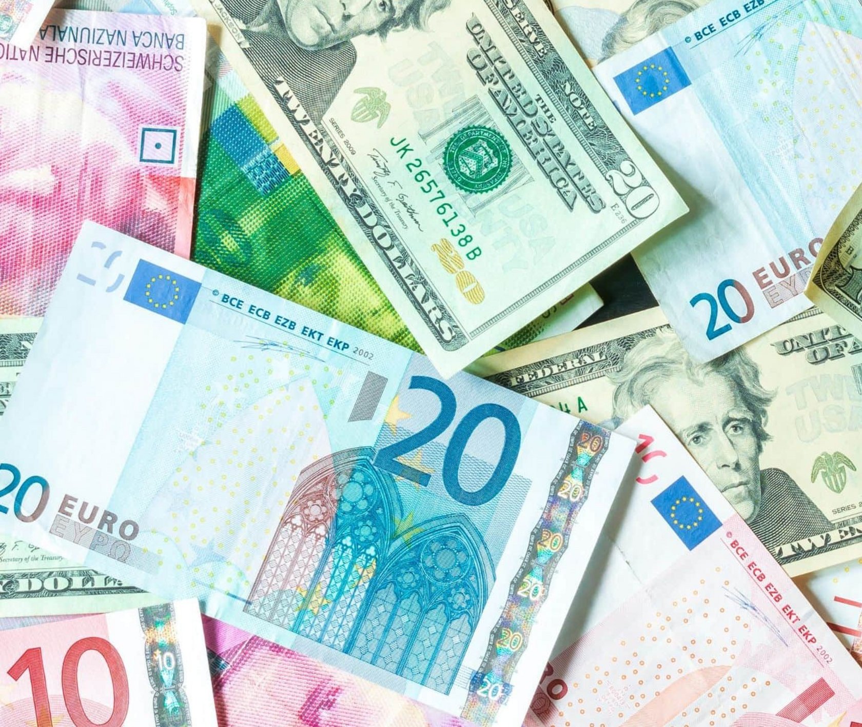 Mehrere Geldscheine verschiedener Währungen, darunter Euro, US-Dollar und Pfund, liegen überlappend auf einer Fläche