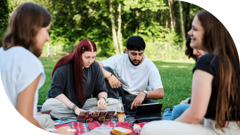 Studierende sitzen auf einer Wiese und lernen gemeinsam.