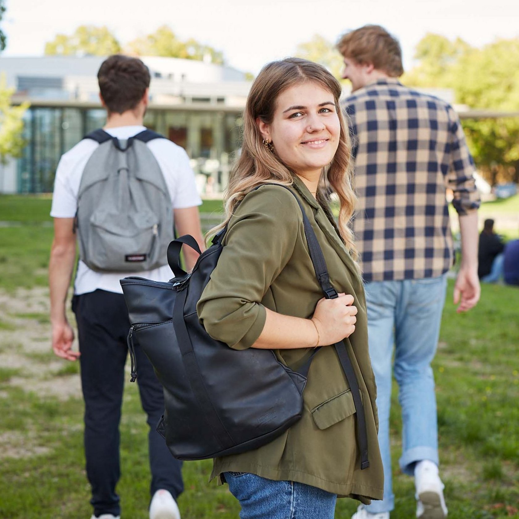 Eine Studentin läuft mit weiteren Studis auf ein Hochschulgebäude zu.